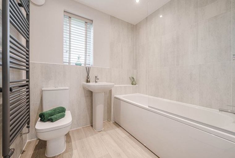 A bathroom with a bathtub, toilet, sink, and heated towel rail.