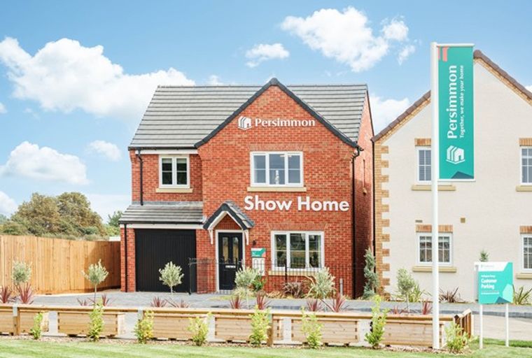 A red brick house with a garage and a sign that says 'Persimmon Show Home'.