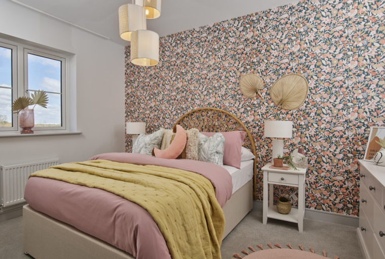 A bedroom with a bed, floral wallpaper, and a window.