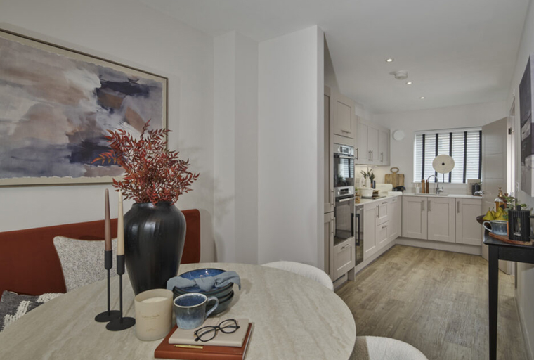 A dining area and kitchen with a table, chairs, and kitchen cabinets.