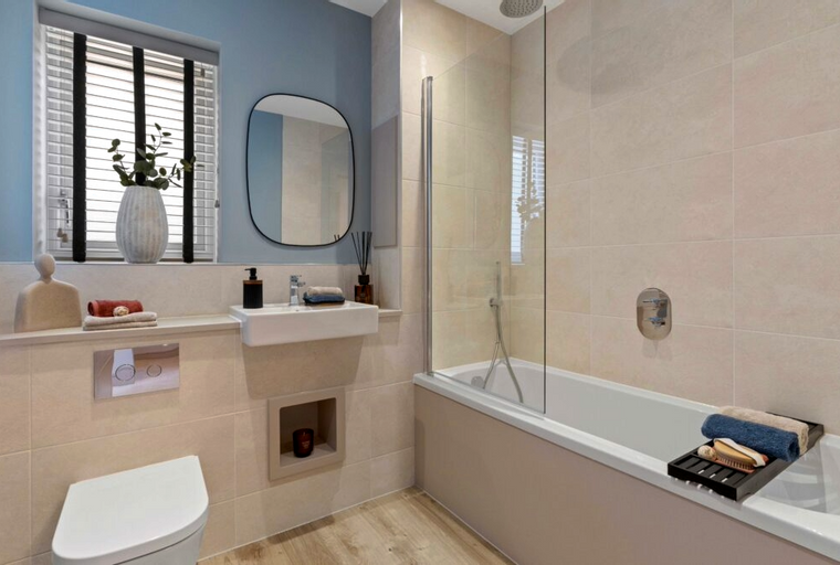 A bathroom with a toilet, sink, and bathtub with a shower screen.