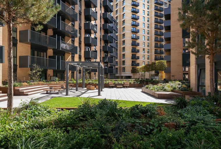 A courtyard with apartment buildings, seating areas, and landscaping.