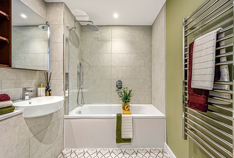 A bathroom with a bathtub, sink, and towel rack.