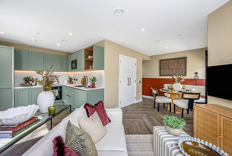 A living room and kitchen area with a sofa, coffee table, and kitchen cabinets.