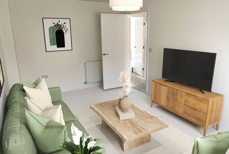 A living room with a green sofa, coffee table, and television.