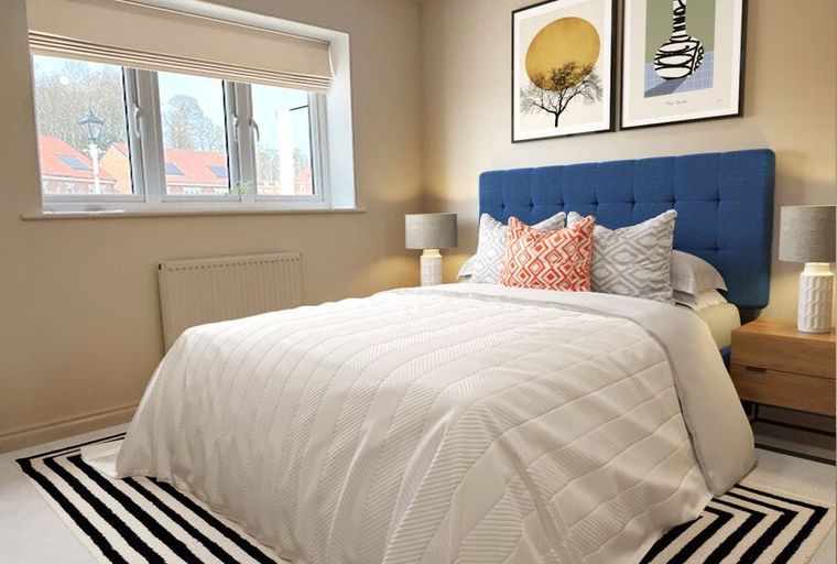 A bedroom with a bed, pillows, lamps, and artwork.