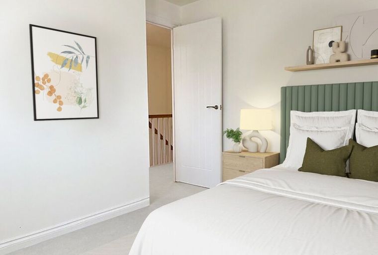 A bedroom with a bed, a green headboard, and a bedside table.