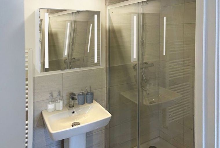 A bathroom with a sink, mirror, and shower.