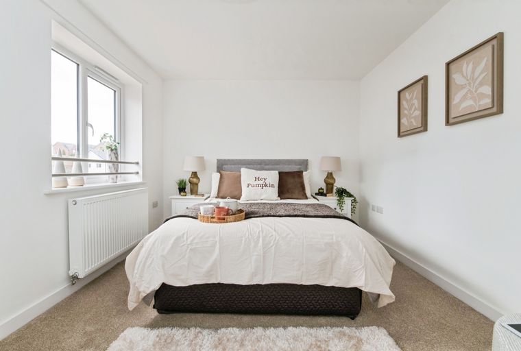 A bedroom with a bed, bedside tables, lamps, and a window.