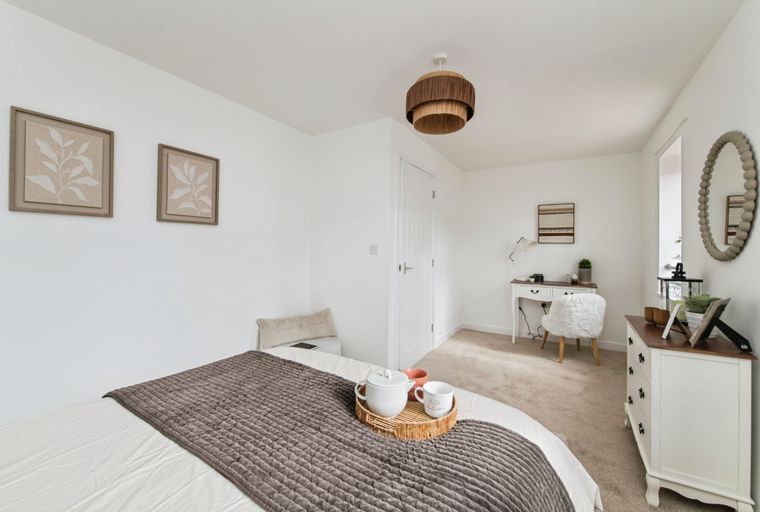 A bedroom with a bed, a vanity desk, a chair, and a mirror.