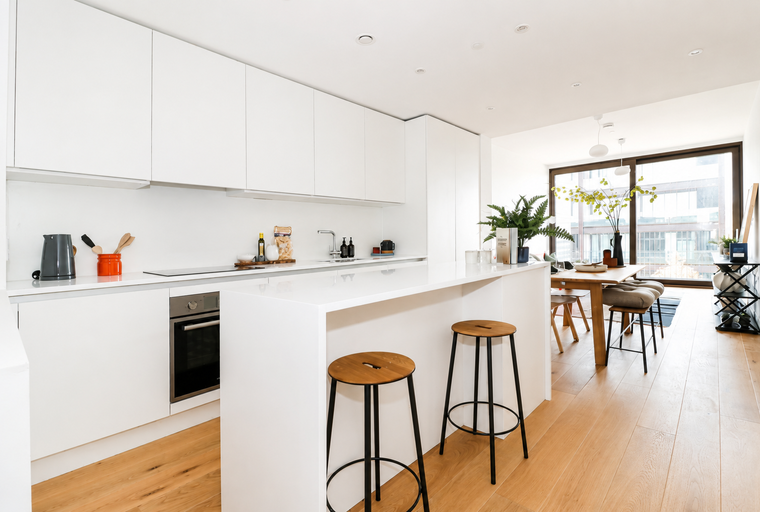 A modern kitchen and dining area with white cabinets, a kitchen island, and a wooden dining table.