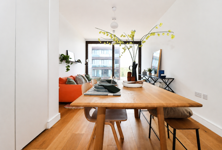 A dining table set for a meal in front of a large window with a sofa in the background.