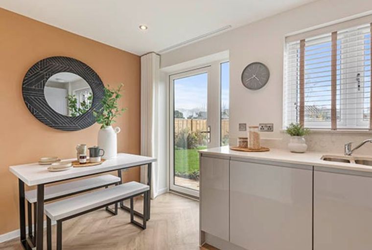 A dining area and kitchen with a table, benches, and cabinets.