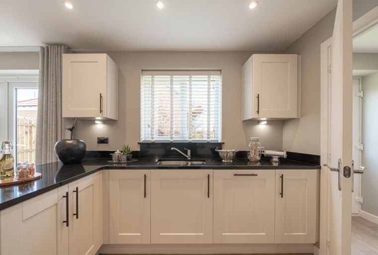 A kitchen with cream cabinets, black countertops, and a window.