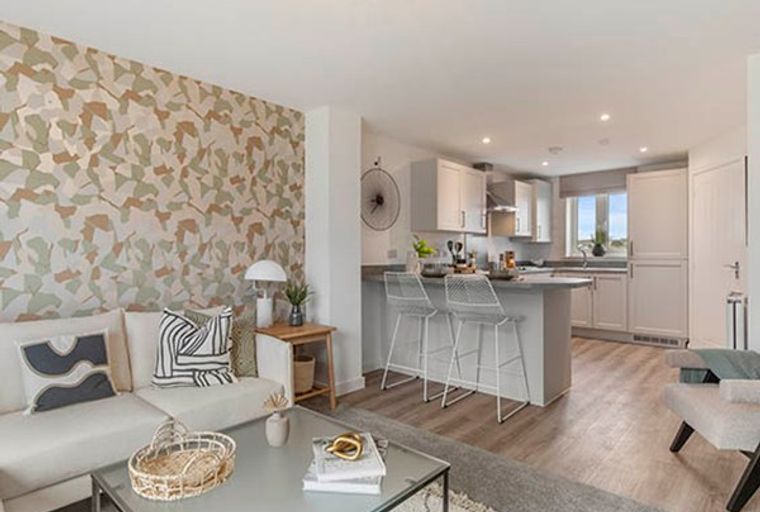 A living room and kitchen area with a sofa, coffee table, and kitchen island with bar stools.