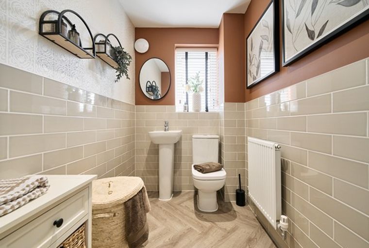 A bathroom with a toilet, sink, and tiled walls.