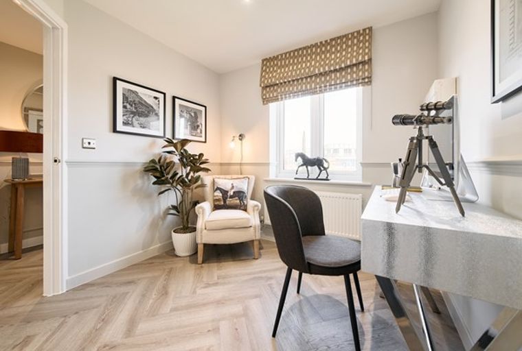 A home office with a desk, chair, armchair, and a window.