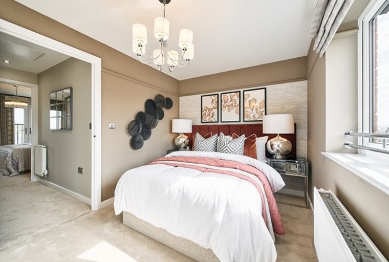 A bedroom with a bed, pillows, wall art, and a chandelier.