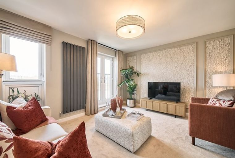 A living room with a sofa, ottoman, television, and a window.