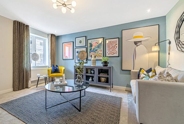 A living room with a sofa, armchair, coffee table, and artwork on the wall.