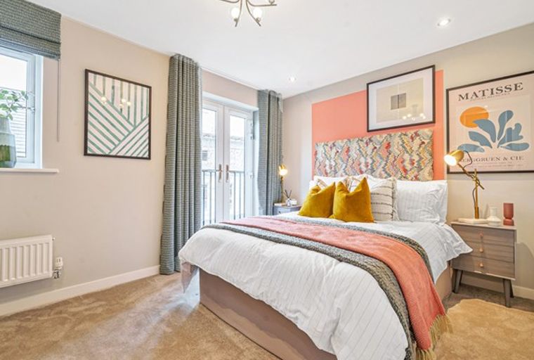 A bedroom with a bed, pillows, blankets, artwork, and curtains.