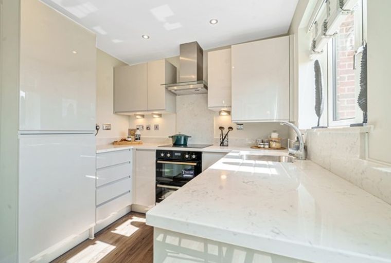 A modern kitchen with white cabinets, a quartz countertop, and an oven.