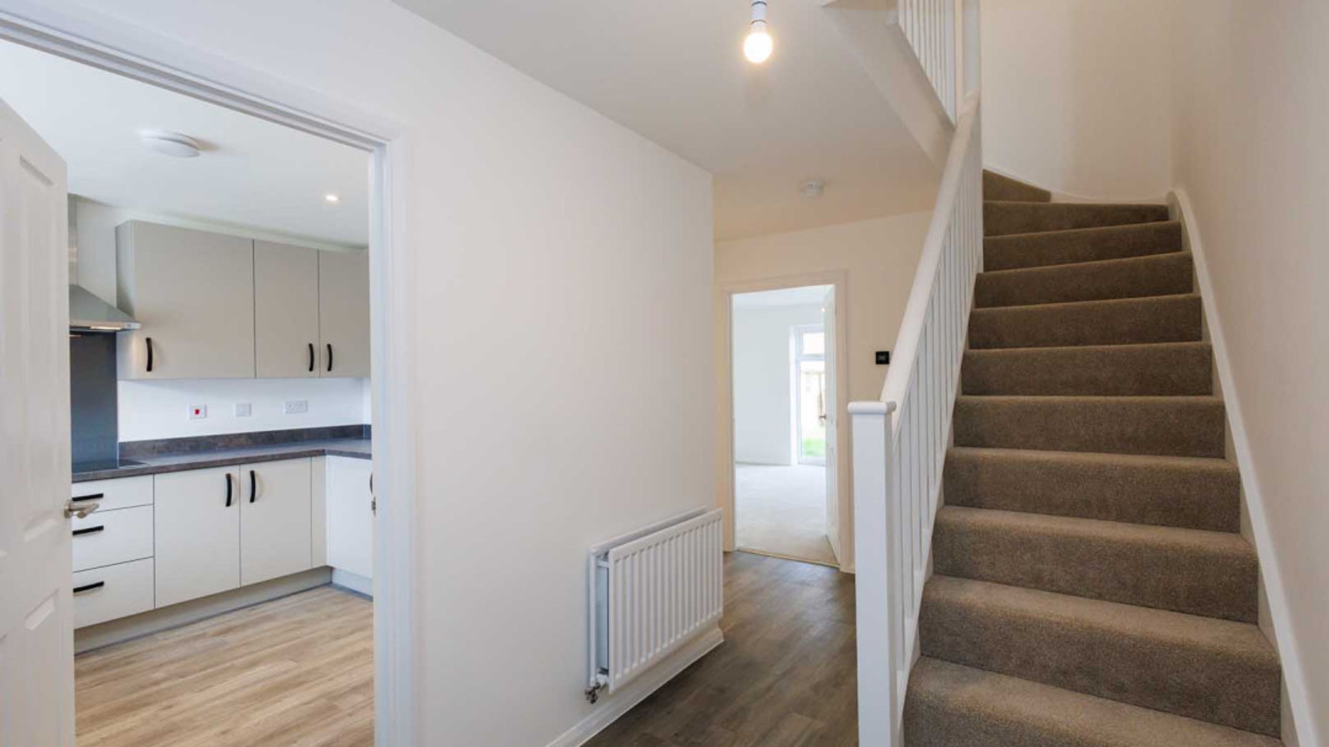 A hallway with a kitchen entrance and a staircase.