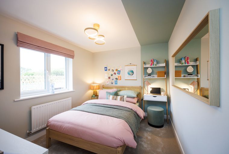 A bedroom with a bed, a desk, and a window.