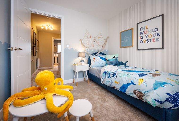 A child's bedroom with ocean-themed bedding and a large octopus stuffed animal.