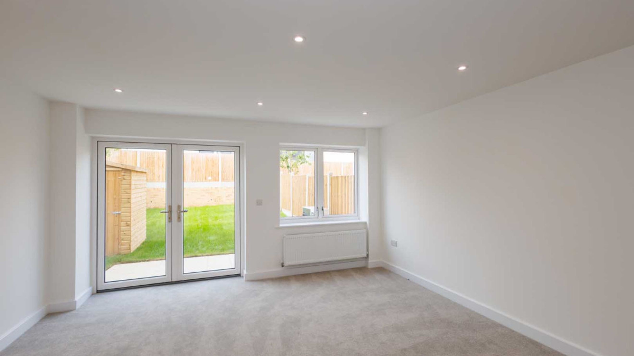 A living room with double doors, a window, and a radiator.
