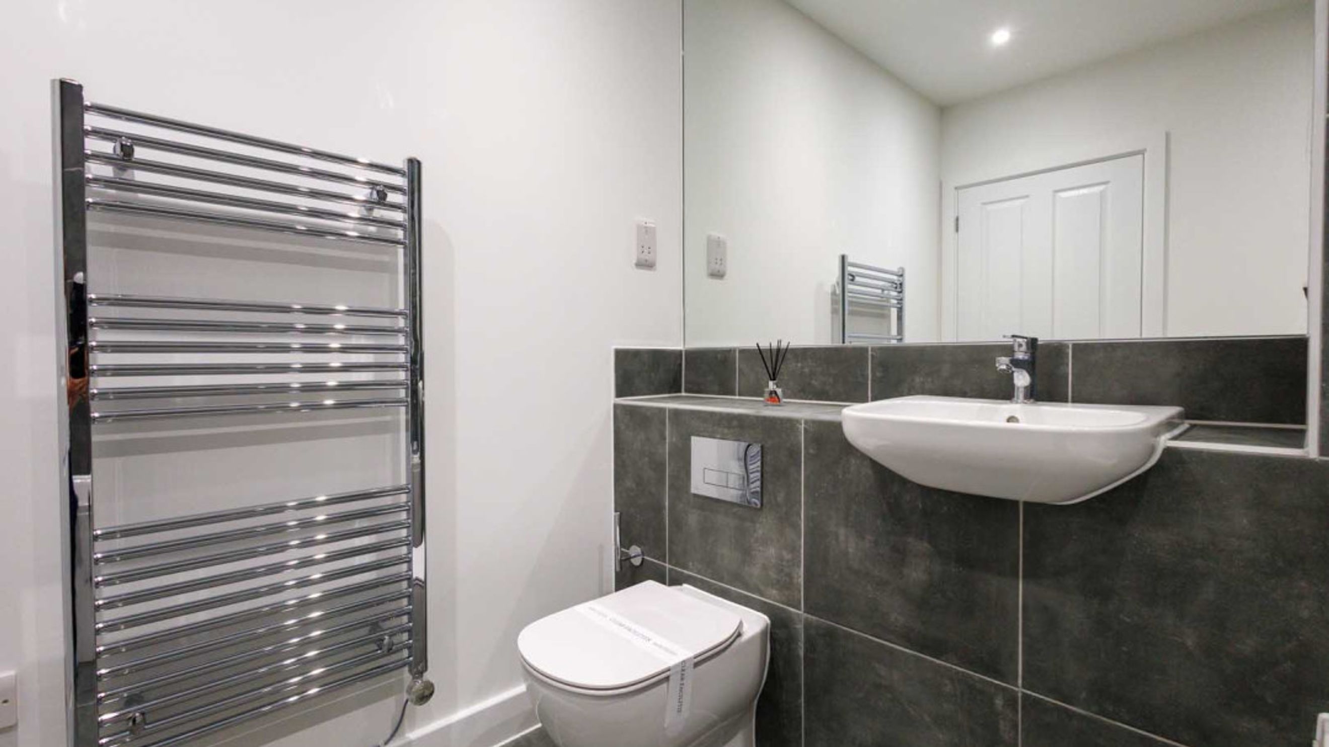 A bathroom with a toilet, sink, and heated towel rail.