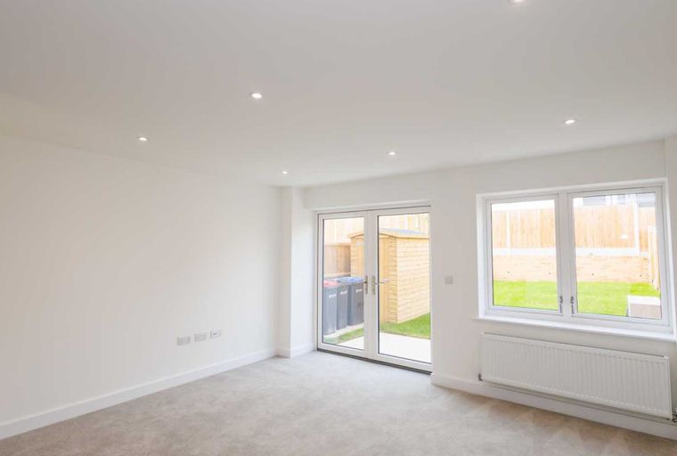 A living room with double doors leading to a garden and a window overlooking the garden.