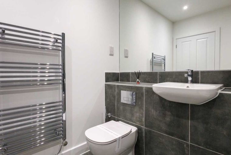 A bathroom with a toilet, sink, and heated towel rail.