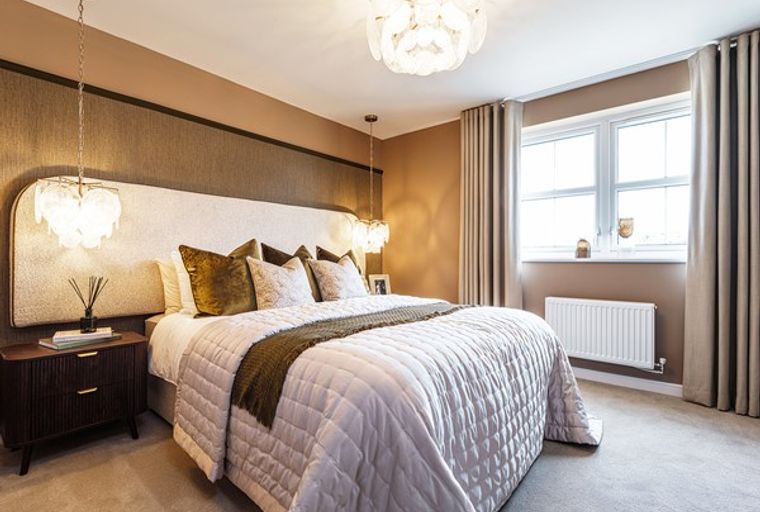 A bedroom with a bed, headboard, pendant lights, bedside table, and a window with curtains.