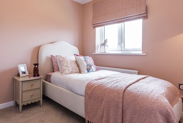 A bedroom with a bed, pillows, a blanket, a bedside table, and a window.