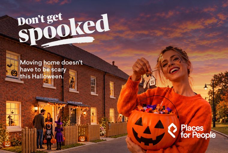 A woman holding a pumpkin bucket full of candy and house keys in front of a brick house decorated for Halloween.