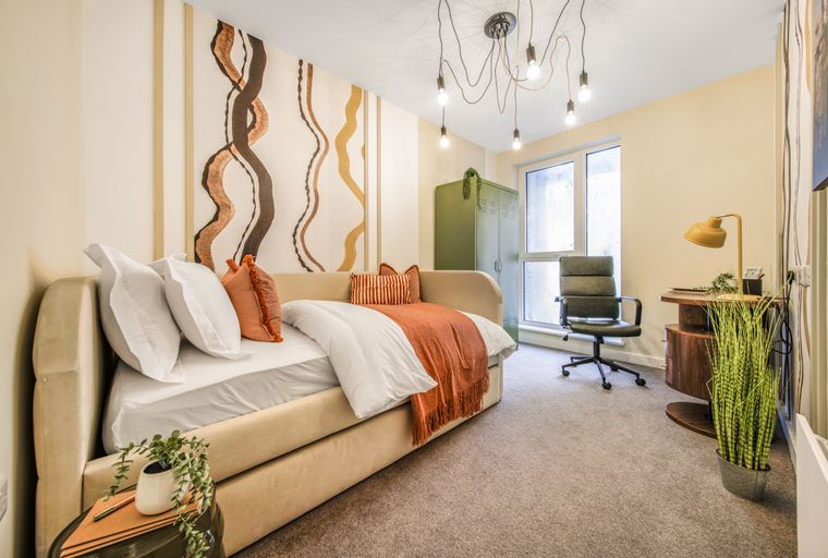 A studio apartment with a bed, desk, and storage cabinet.