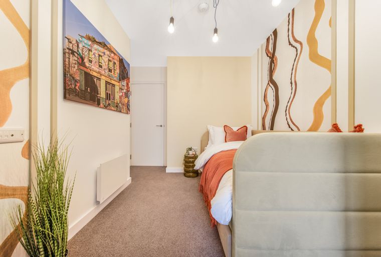 A bedroom with a bed, wall art, and a plant.