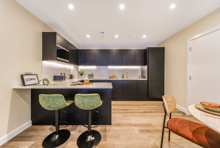 A modern kitchen with dark cabinets, a kitchen island with bar stools, and a dining area.