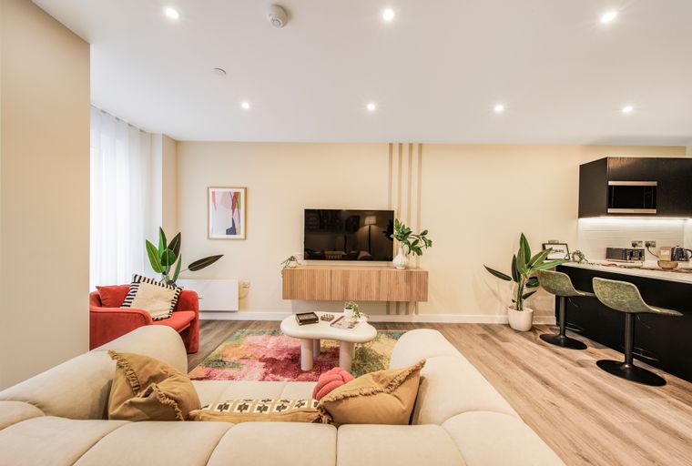 A living room and kitchen area with a sofa, coffee table, TV, and kitchen island with bar stools.