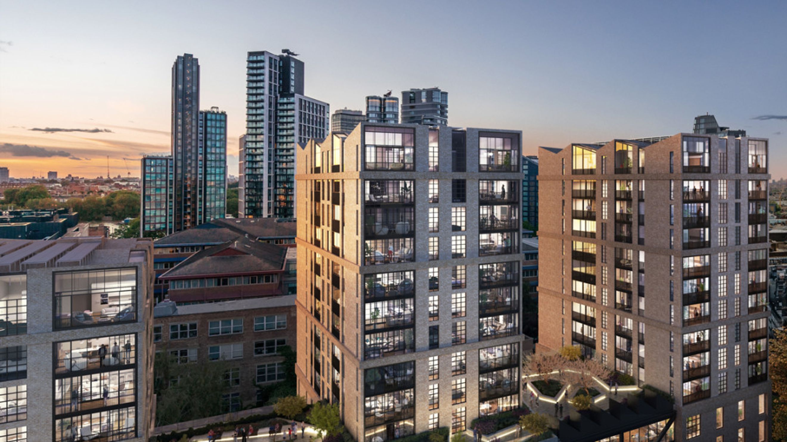 A view of modern apartment buildings at dusk with many windows and balconies.