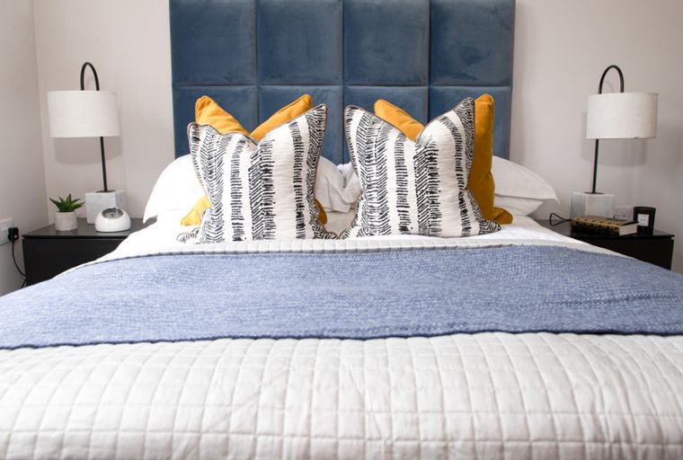 A bedroom with a bed, pillows, and bedside tables.