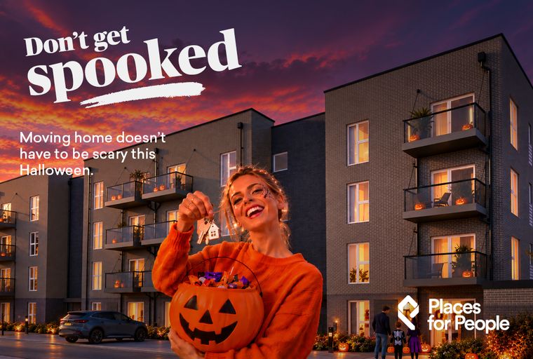 A woman holding a pumpkin bucket full of candy and keys in front of an apartment building decorated for Halloween.