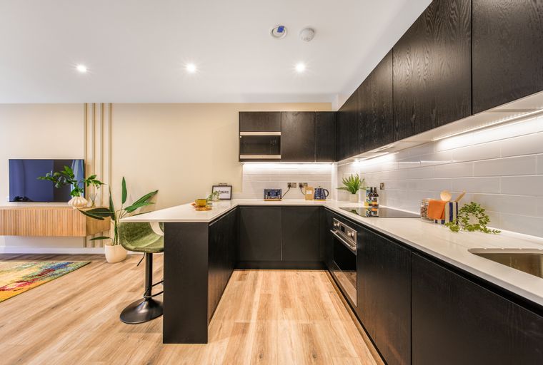 A modern U-shaped kitchen with dark wood cabinets and white countertops.