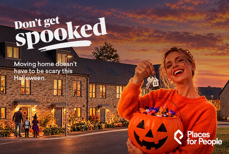 A woman holding a pumpkin candy bucket and house keys in front of a row of houses decorated for Halloween.