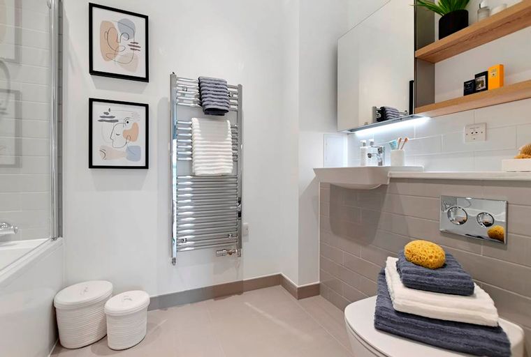 A bathroom with a sink, towel warmer, and artwork.