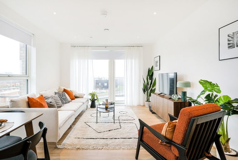 A living room with a sofa, coffee table, rug, and television.