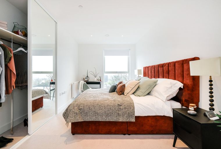 A bedroom with a bed, headboard, pillows, and a nightstand.