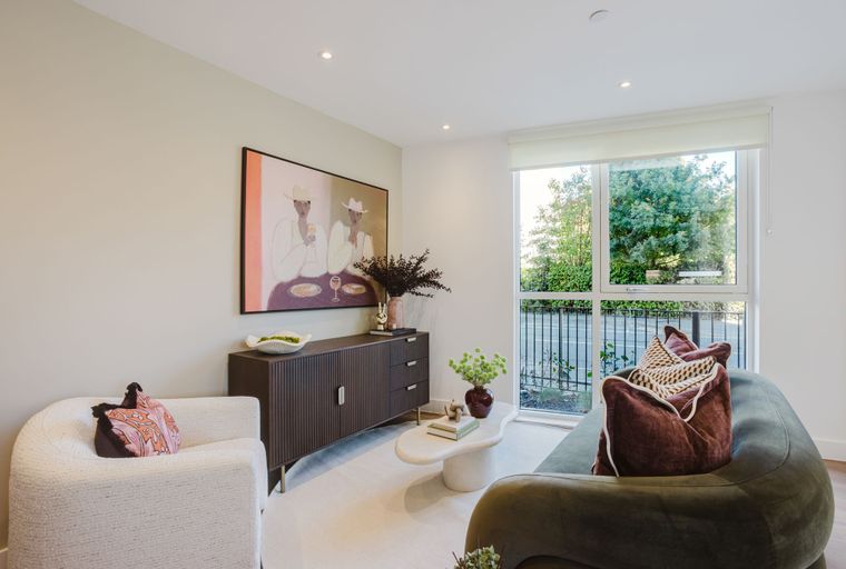 A living room with a sofa, armchair, coffee table, and a large window.