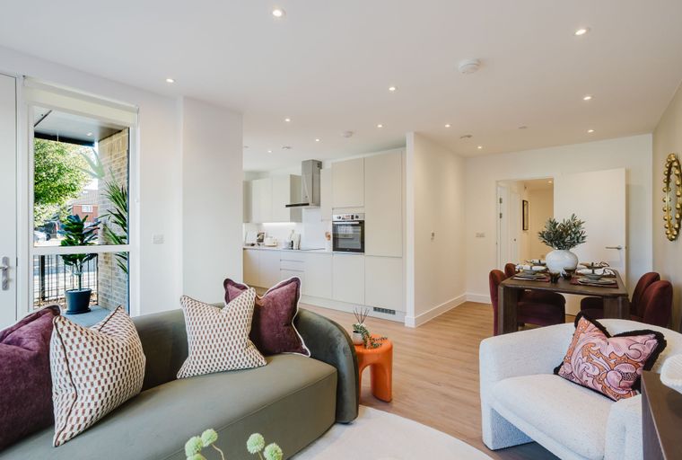 A living room and kitchen area with a sofa, chairs, and a dining table.